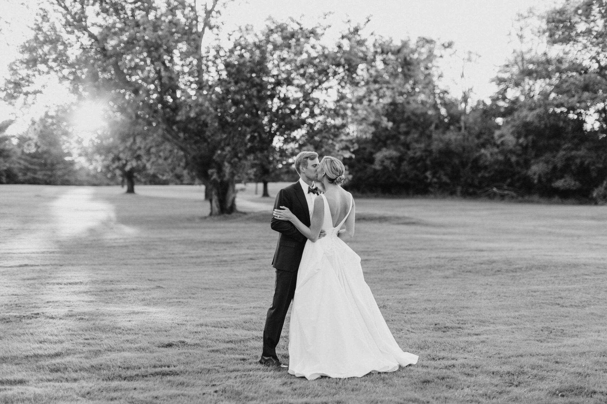 Naples Wedding Photographer Couple in a big private yard kissing with the brides back to us